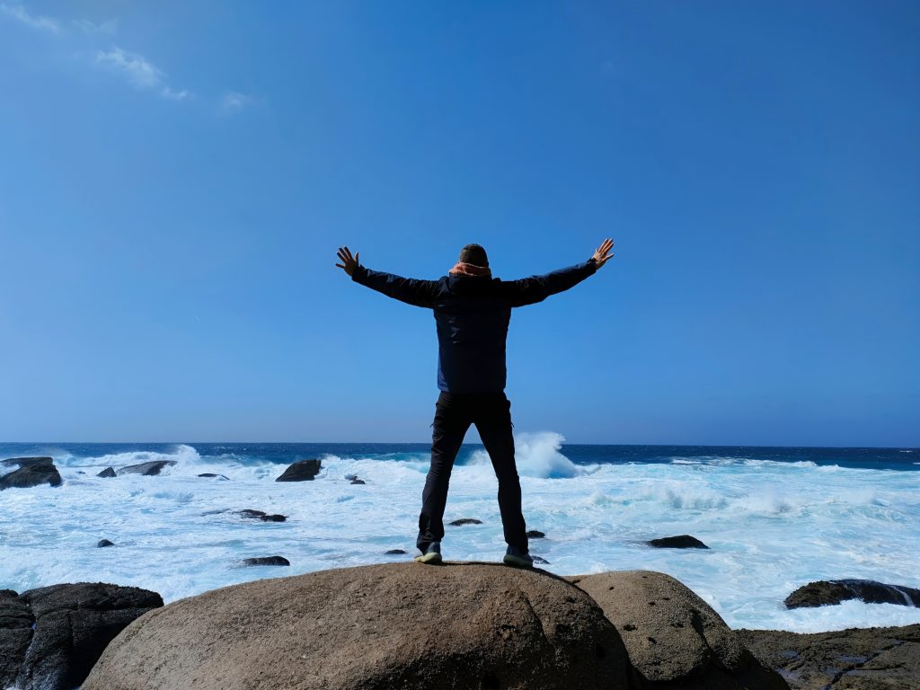 Momento di libertà e realizzazione davanti all'oceano, metafora del completamento di un percorso di crescita personale
